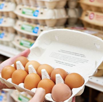 hands with packages of eggs in store