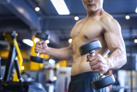 Handsome asian man with dumbbell in the sports gym, bodybuilding concept