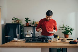 handsome cheerful man standing in a kitchen preparing a meal