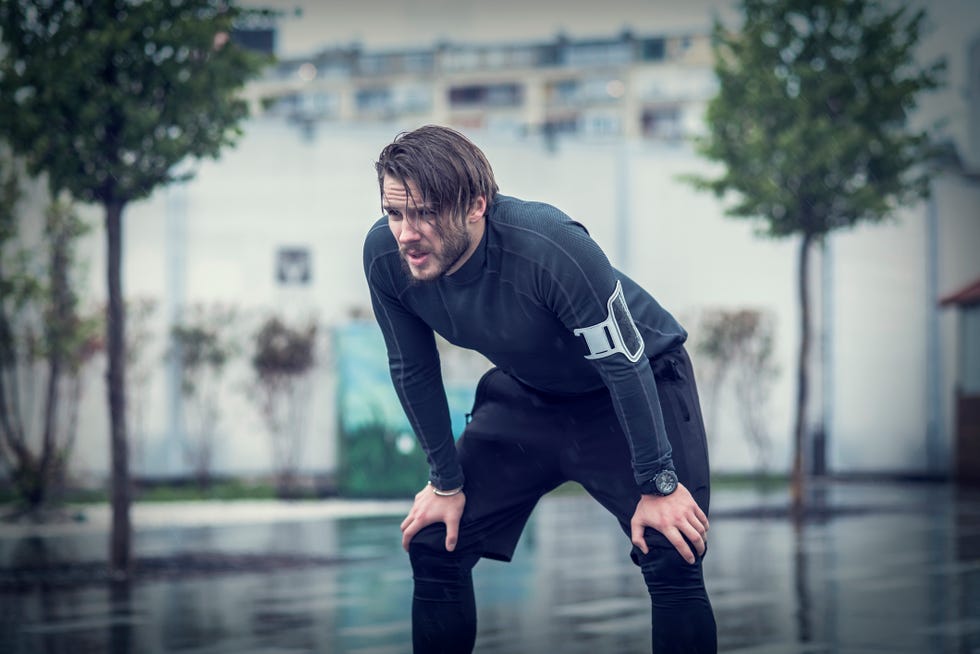 handsome fit man taking a break after workout in the rain