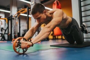 handsome man working out with fitness wheel in gym