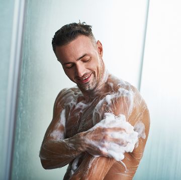シャワーを浴びながら、身体を洗う男性