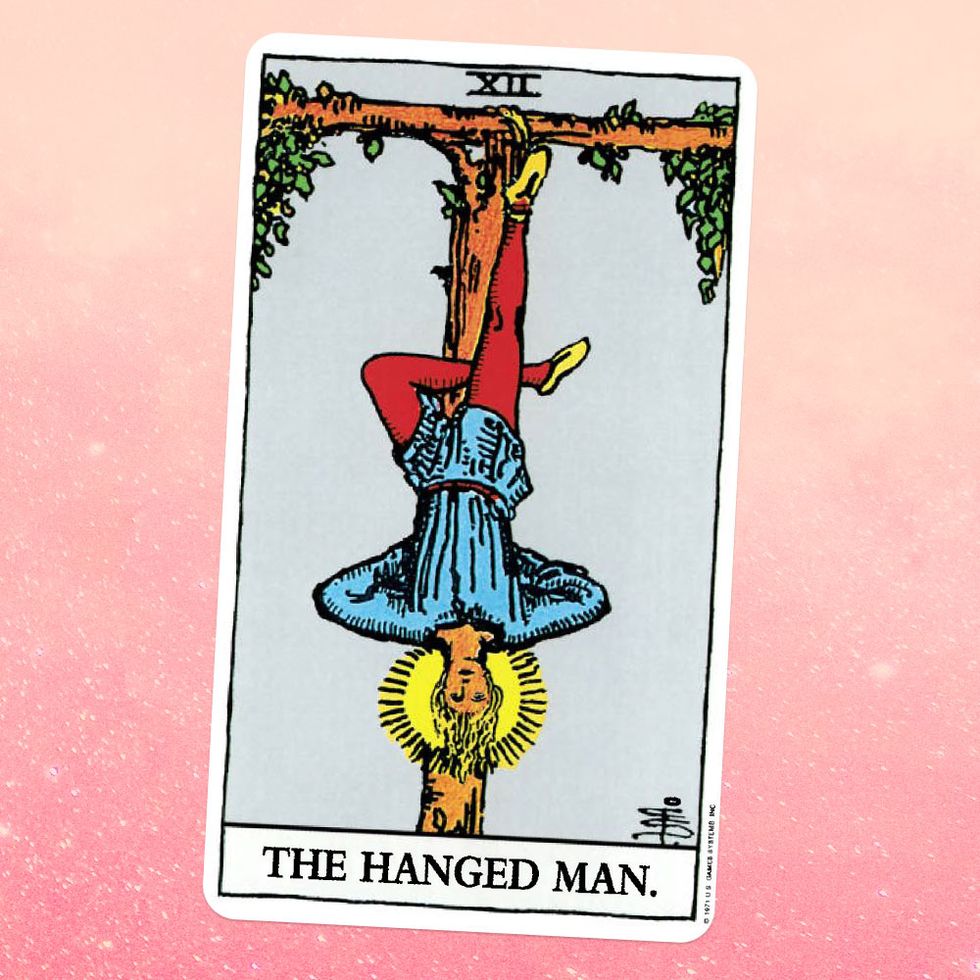 the tarot card the hanged man, showing a man hanging upside down, with one foot tied to a tree