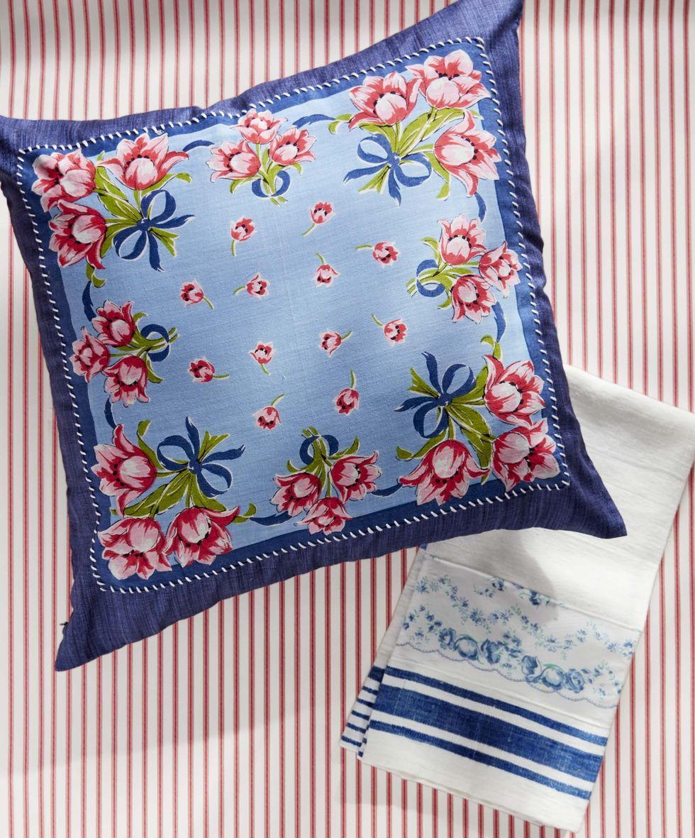 navy throw pillow with a blue, pink, and green floral handkerchief whipstiched to the front, beside a blue and white tea towel also embellished with a handkerchief