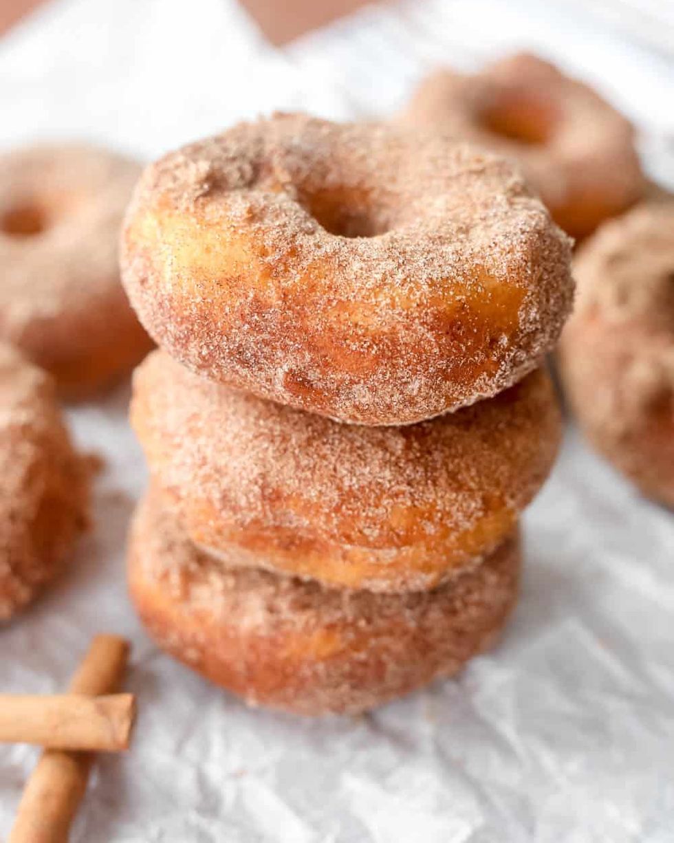 cinnamon sugar biscuit donuts stacked up with cinnamon sticks on side