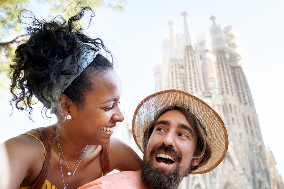 a justmarried couple taking a selfie with the sagrada familia in the background
