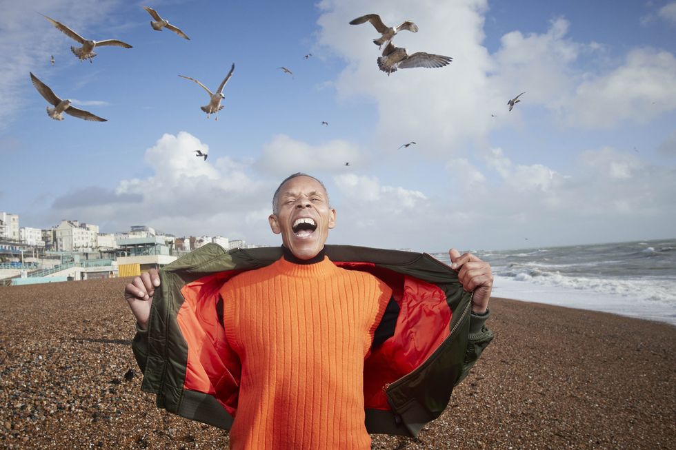 senior man screaming while birds flying at beach on sunny day
