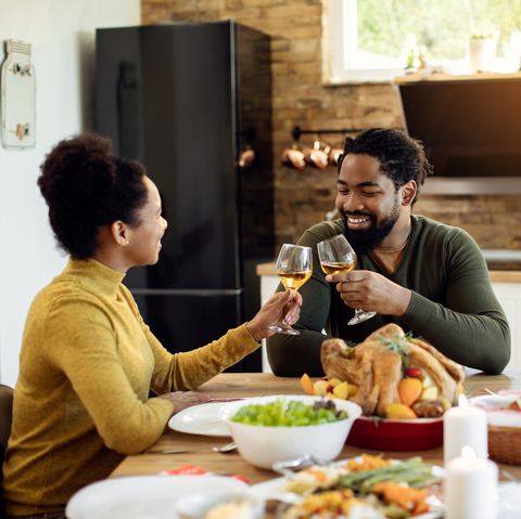 happy couple toasting during thanksgiving meal in dining room