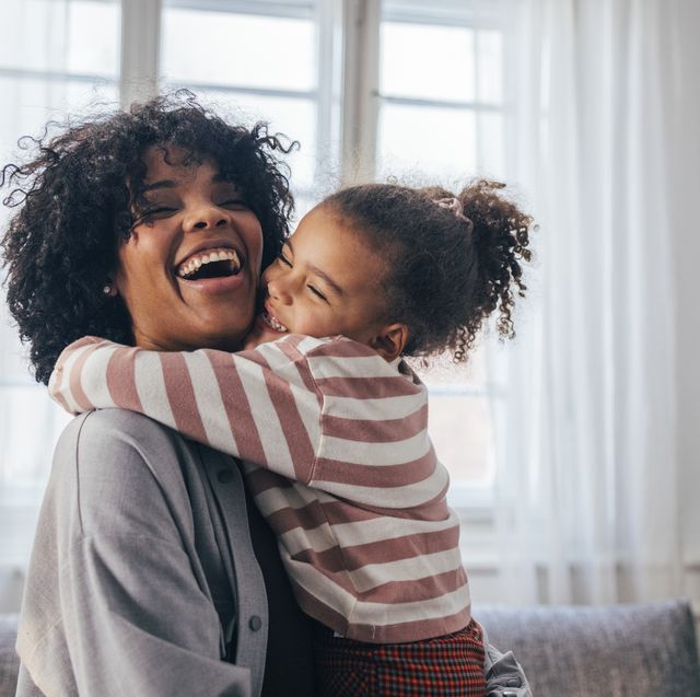 a happy african american woman being hugged by her cute little daughter at home
