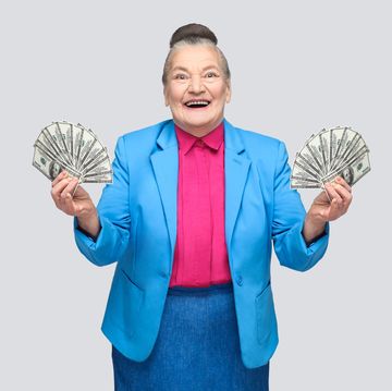 happy aged woman holding many american dollars