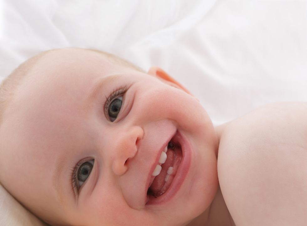 bebé feliz enseñando sus primeros dientes de leche