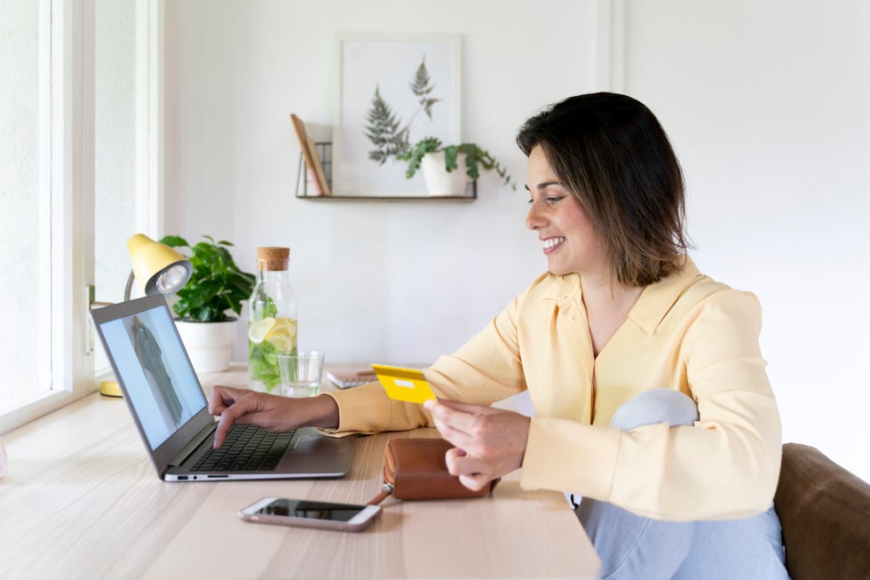 una mujer se dispone a realizar compras online con ordenador y tarjeta de crédito