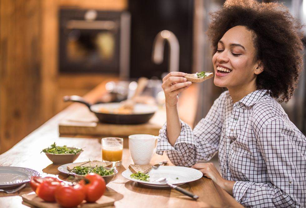 Happy black woman enjoying during breakfast time in the kitchen.