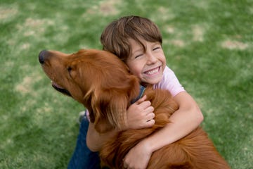 a young boy hugging a golden retriever dog