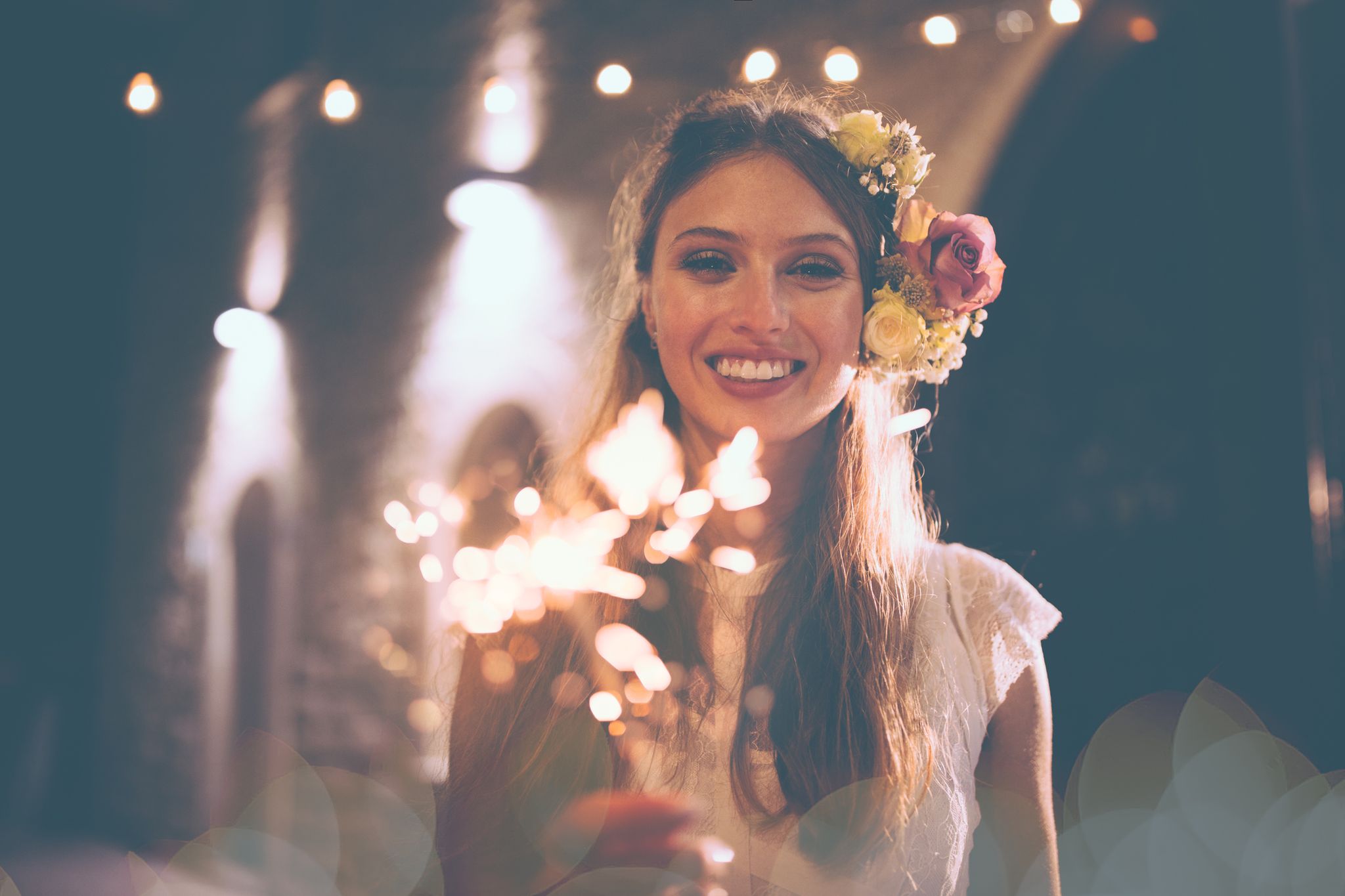 Happy bride in white wedding dress holding sparklers and celebrating
