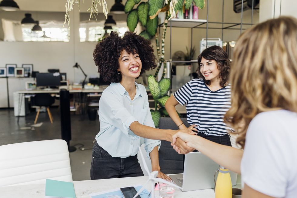 woman shaking hand with colleague at work place