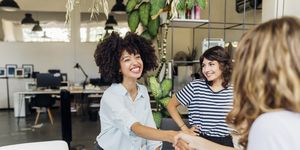 happy businesswoman shaking hand with colleague at work place
