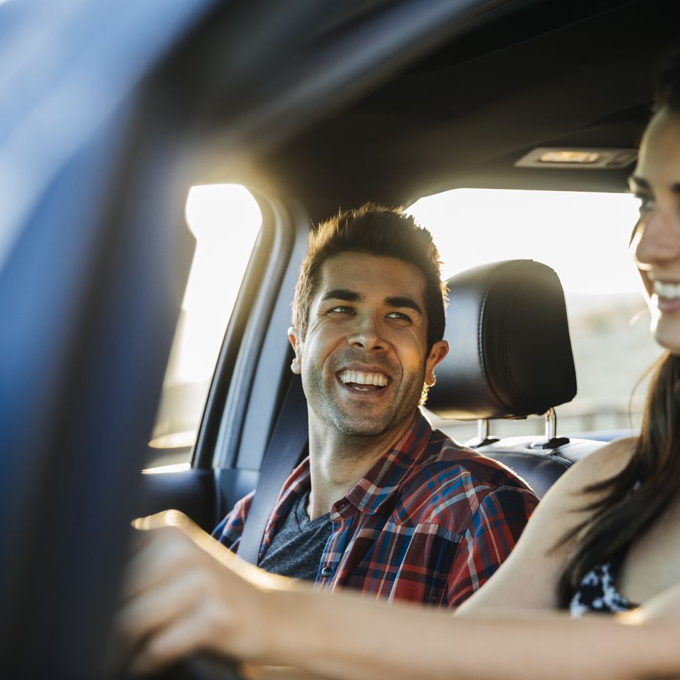 staycation ideas - Happy couple driving in car on road trip