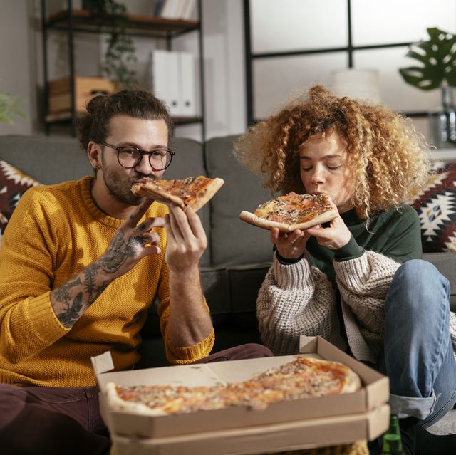 happy couple eating pizza at home