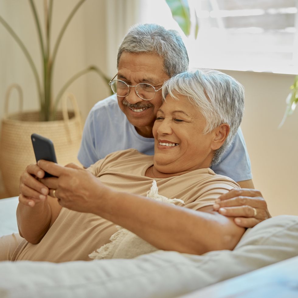 happy, couple embrace and reading from phone for communication, social media and news smile, affection and a senior man and woman on mobile app for notification, update and browsing retirement home