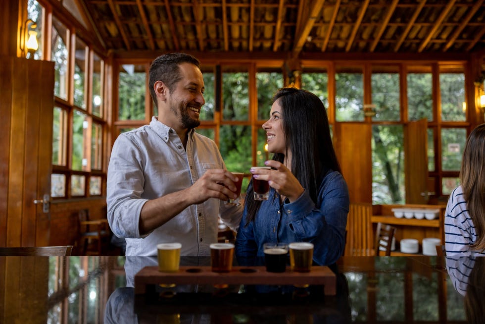 happy couple making a toast while trying different beers at a brewery