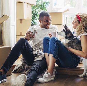Happy couple playing with dog while sitting at doorway in new house