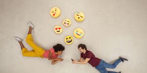 happy couple texting on their smart phones, sending emojies