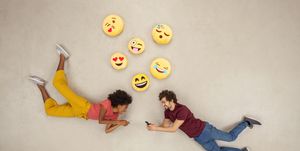 happy couple texting on their smart phones, sending emojies