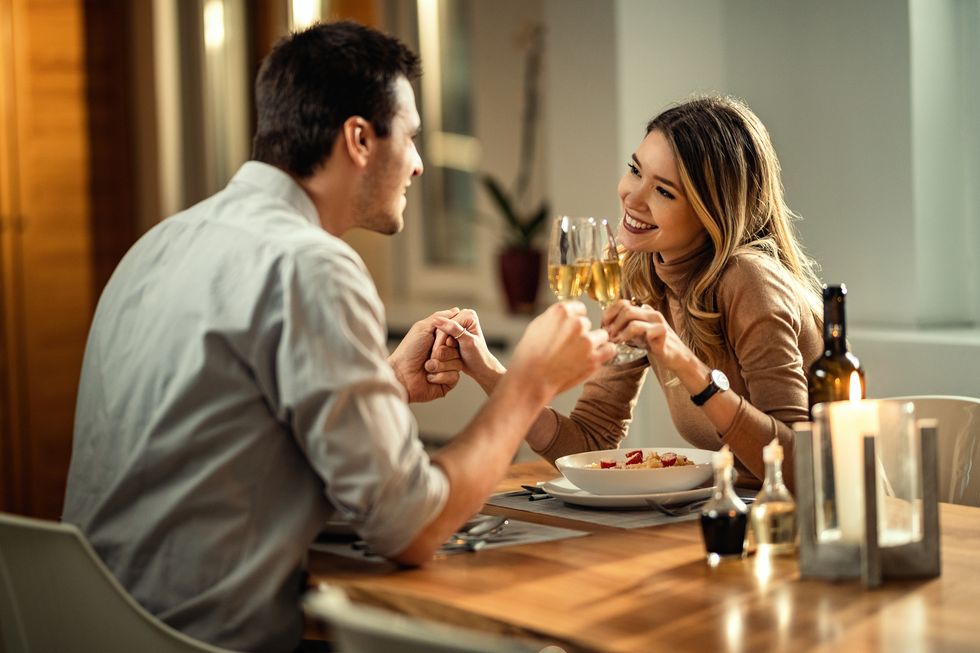happy couple toasting with champagne during dinner at dining table