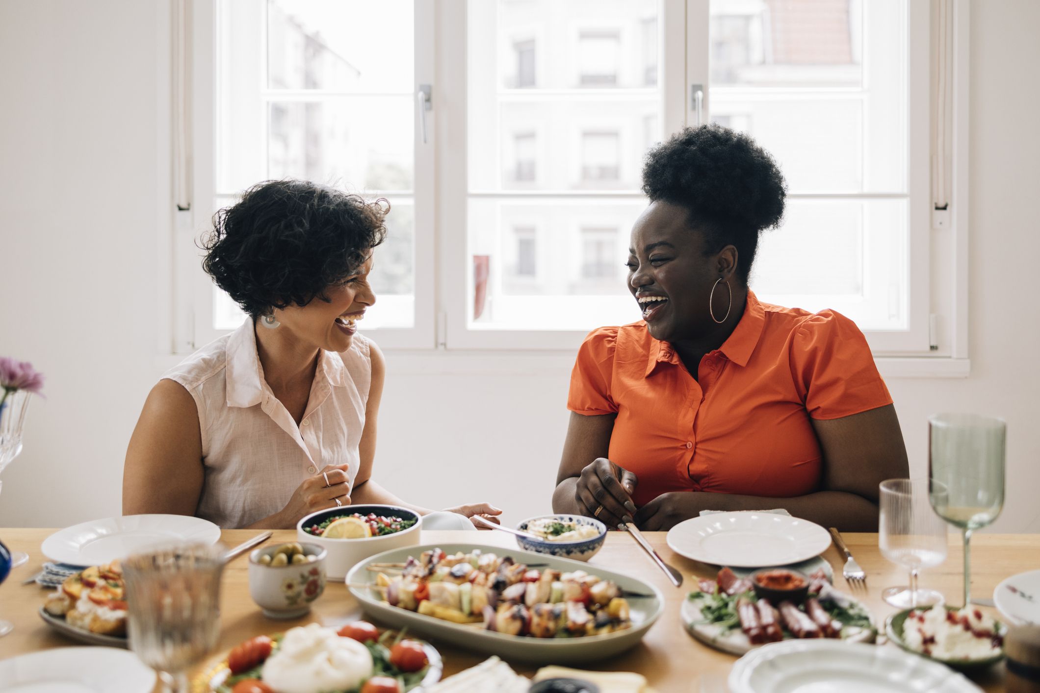 https://hips.hearstapps.com/hmg-prod/images/happy-diverse-friends-sitting-at-the-table-and-royalty-free-image-1686169680.jpg