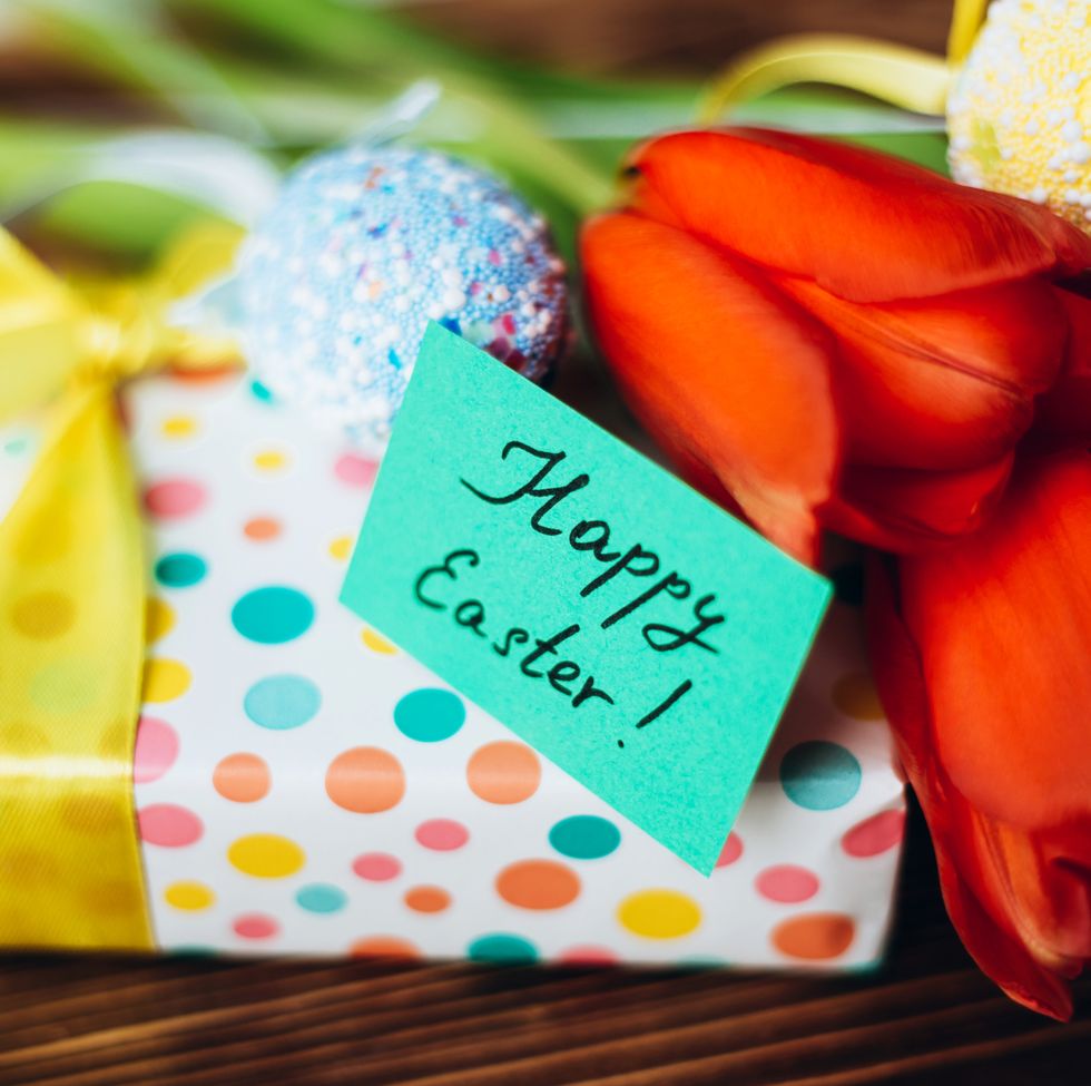 beautiful orange tulips, eggs and bright gift box with happy easter card on wooden background