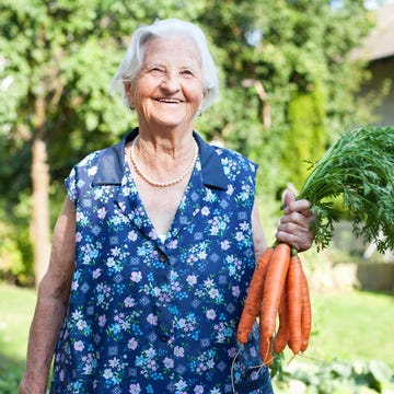 happy elderly lady holding a bunch of carrots