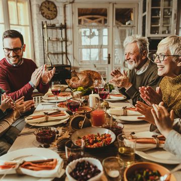 happy extended family applauding during thanksgiving meal at dining table