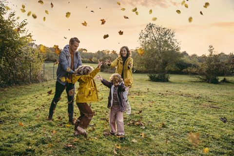 Happy family playing with autumn leaves on the meadow
