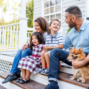 happy family with two kids sitting in front of american porch