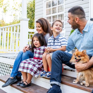 happy family with two kids sitting in front of american porch