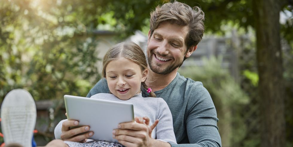 Happy father and daughter using tablet together in garden
