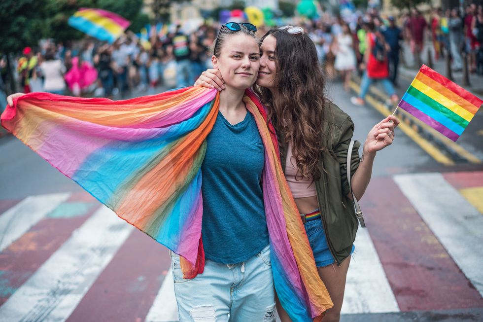 happy female couple hugging and kissing at the gay pride parade