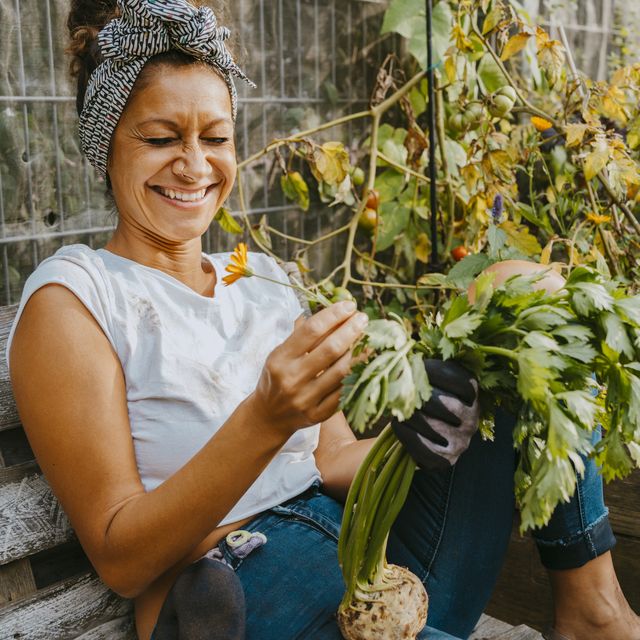 happy female environmentalist with vegetable sitting in urban farm