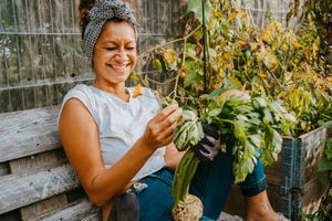 happy female environmentalist with vegetable sitting in urban farm