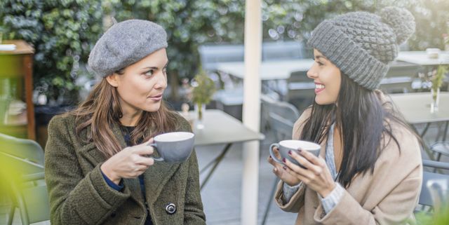 Happy female friends talking at sidewalk cafe