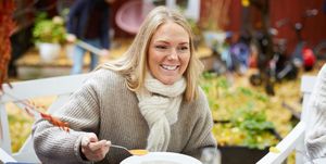 happy female with vegetarian soup sitting by table at yard