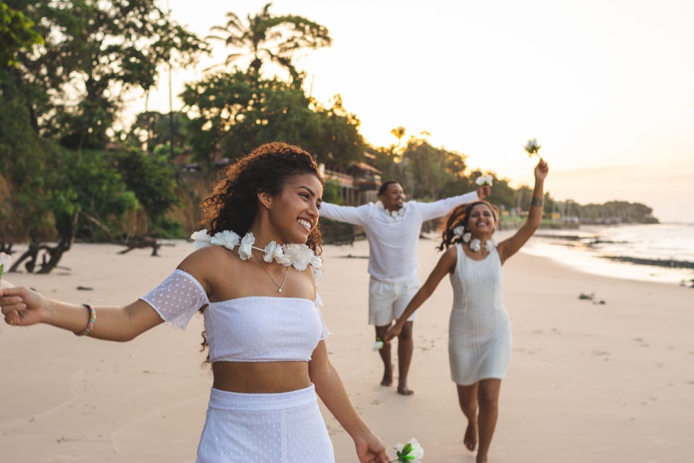 happy friends celebrating reveillon on the beach, running and holding white flowers paraiso beach, mosqueiro