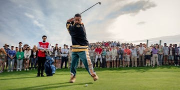 a golfer preparing to swing while surrounded by a large audience