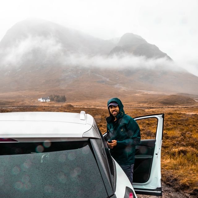 happy guy in a adventure off road with car in the scottish highlands with rain