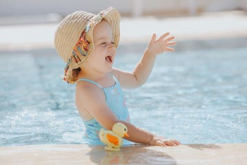 nina en playa feliz con sombrero