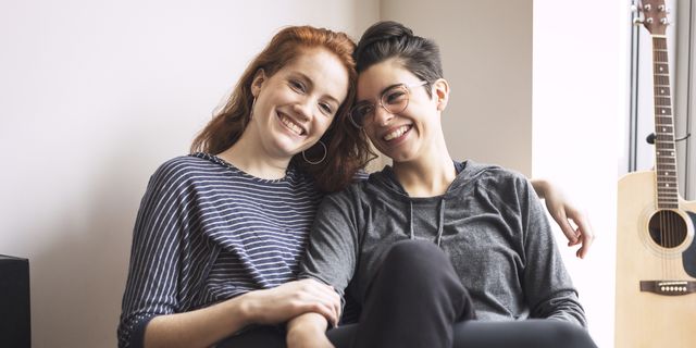 Happy lesbian couple sitting on chair at home