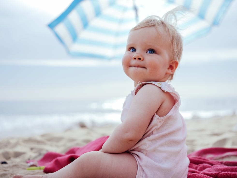 niña en la playa bajo la sombrilla