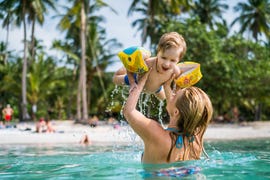 happy little boy having fun in the sea while being held by his mother