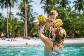 happy little boy having fun in the sea while being held by his mother